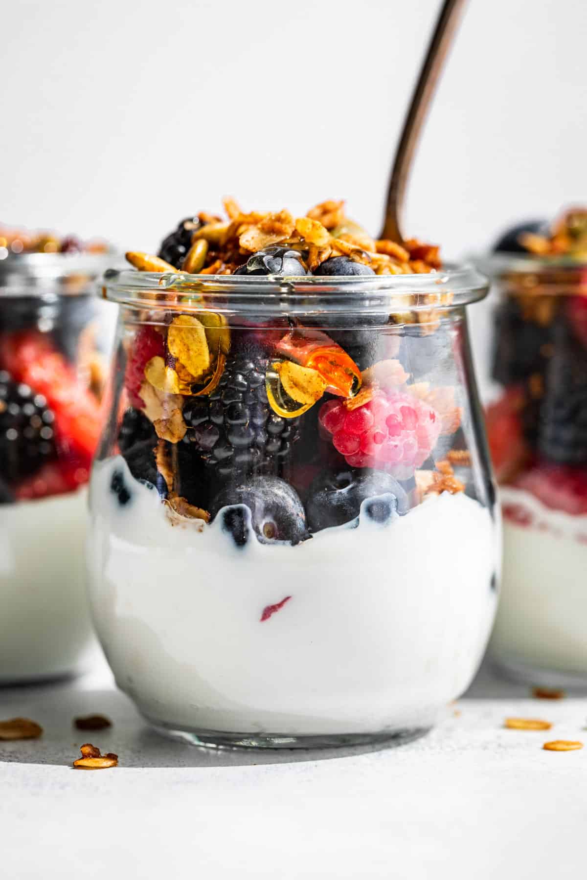 Yogurt, fresh berries, and granola in a clear glass jar.