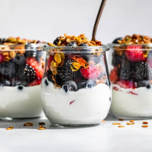 Small glass jars with yogurt, fresh berries, and topped with granola.