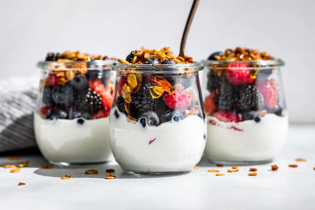Small glass jars with yogurt, fresh berries, and topped with granola.