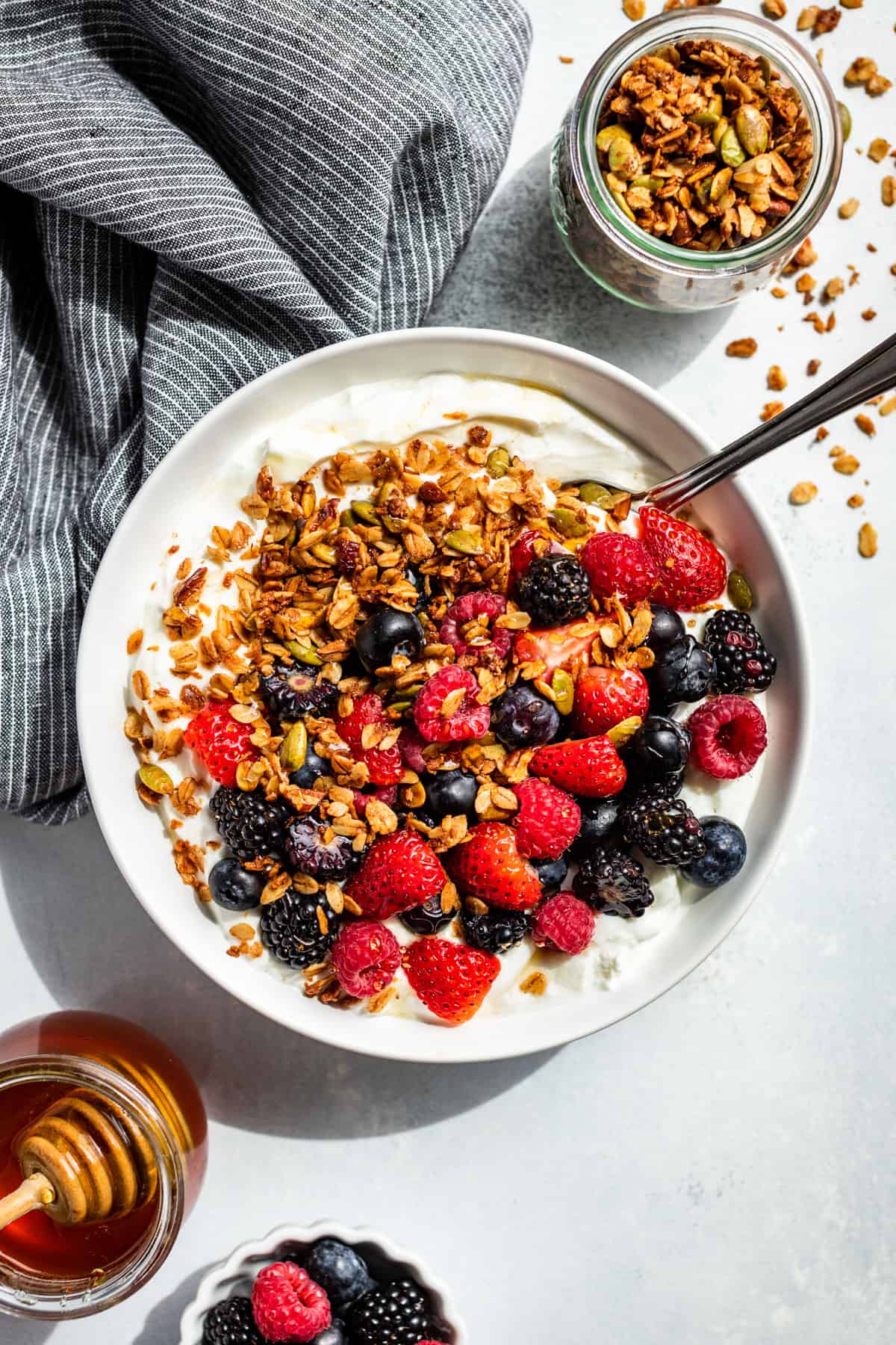 A white bowl with yogurt topped with fresh berries and granola.