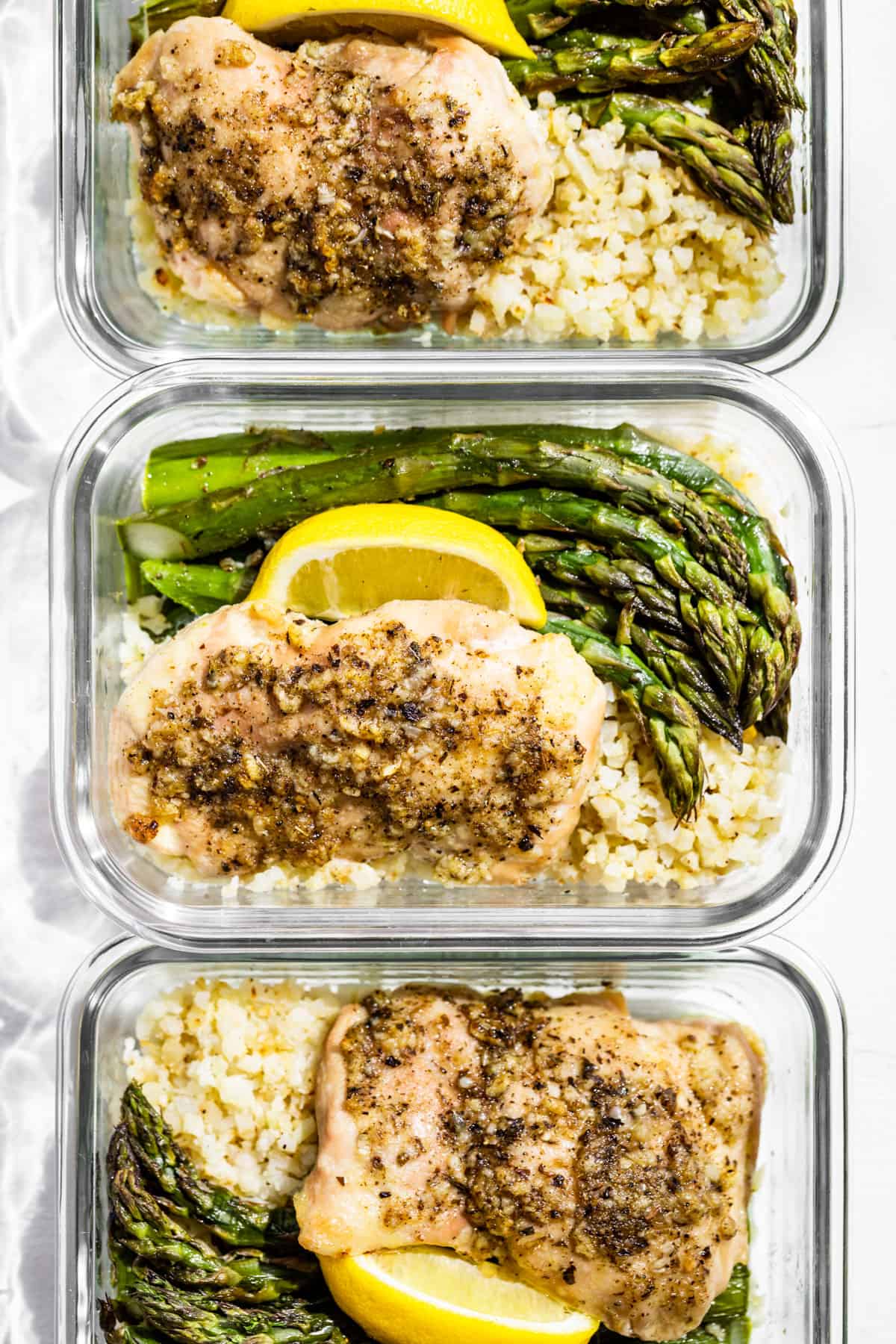Straight down view of the Garlic Herb Chicken and Asparagus in three glass containers.