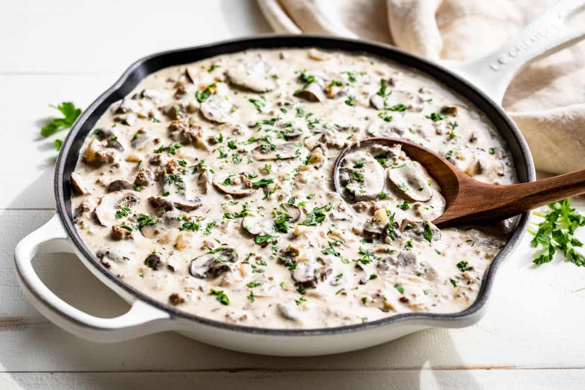 Finished Ground Beef Stroganoff in a white skillet sprinkled with parsley.