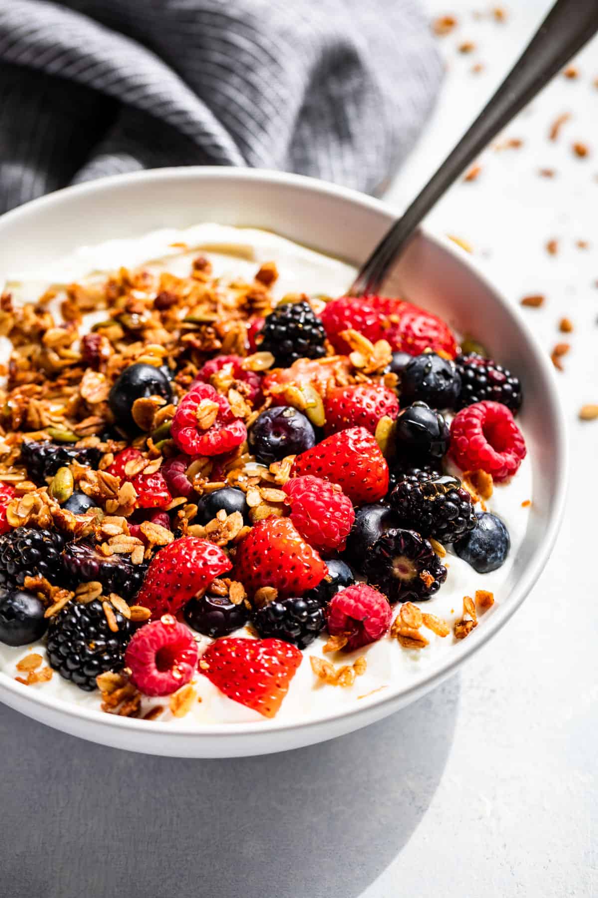 A white bowl with yogurt, fresh berries and topped with granola.