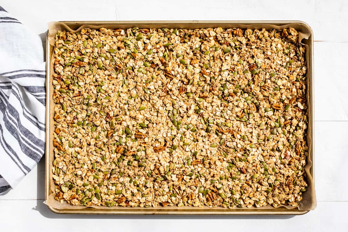 The raw granola mixture spread out on a parchment lined baking sheet.