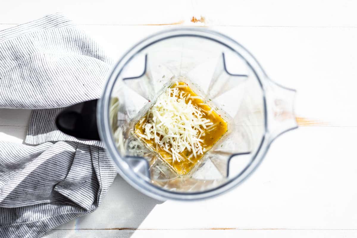 Adding the optional parmesan cheese to the blender with the finished dressing.