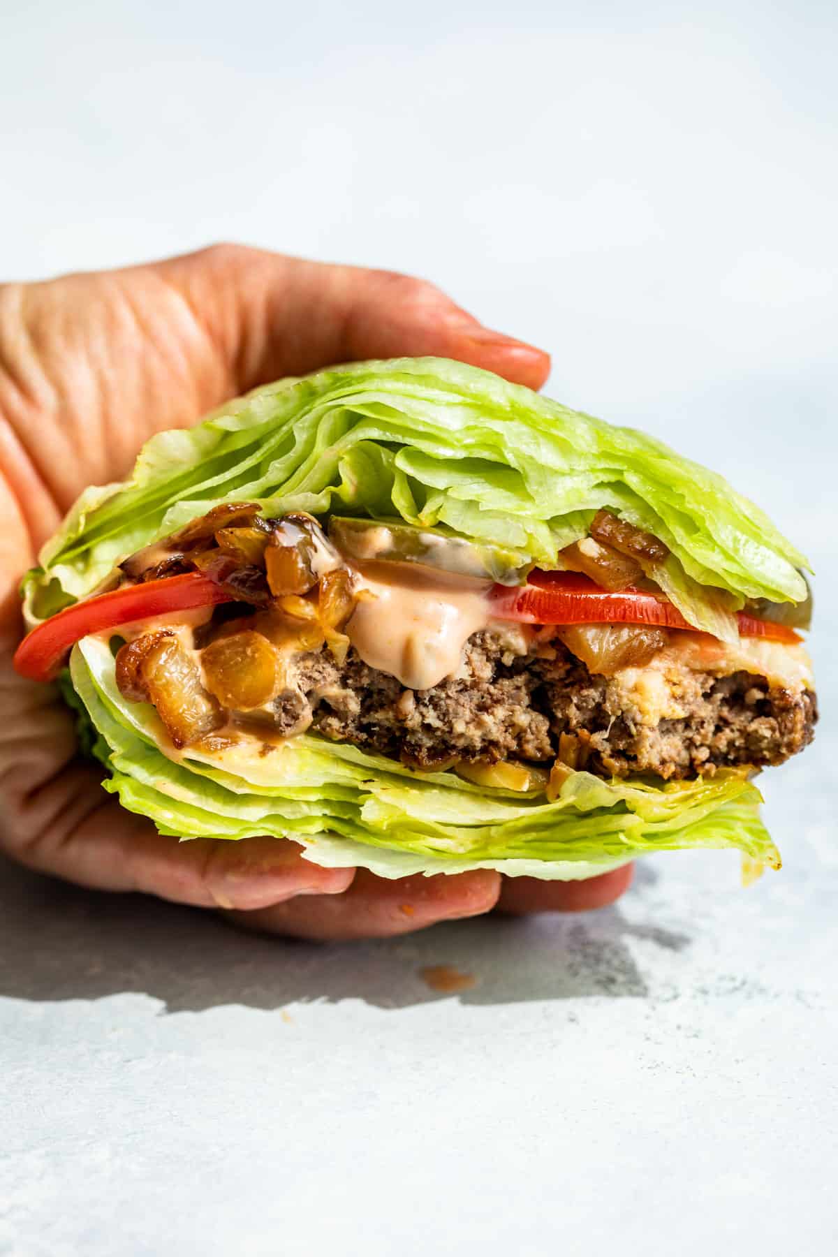 A hand holding a In and Out Burger Lettuce Wrap with bites taken out of it.