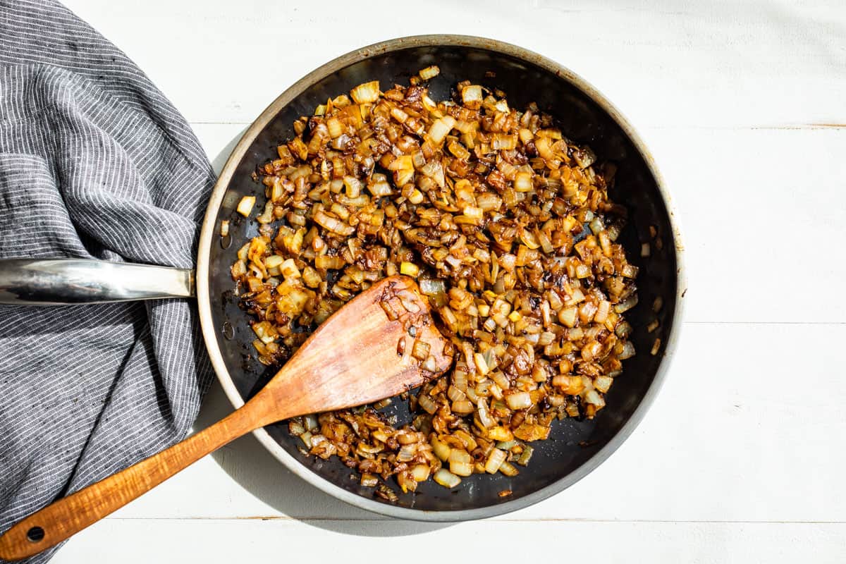 Caramelized onion in a skillet with a wooden spatula.