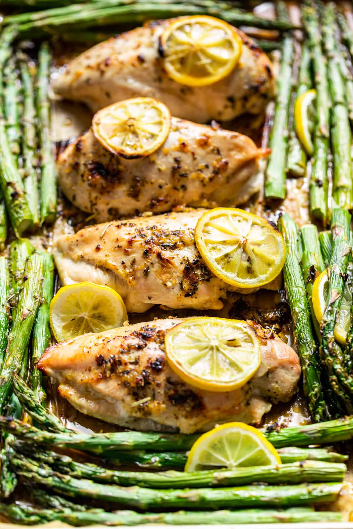 Side close up view of Lemon Chicken and Asparagus topped with lemon slices.