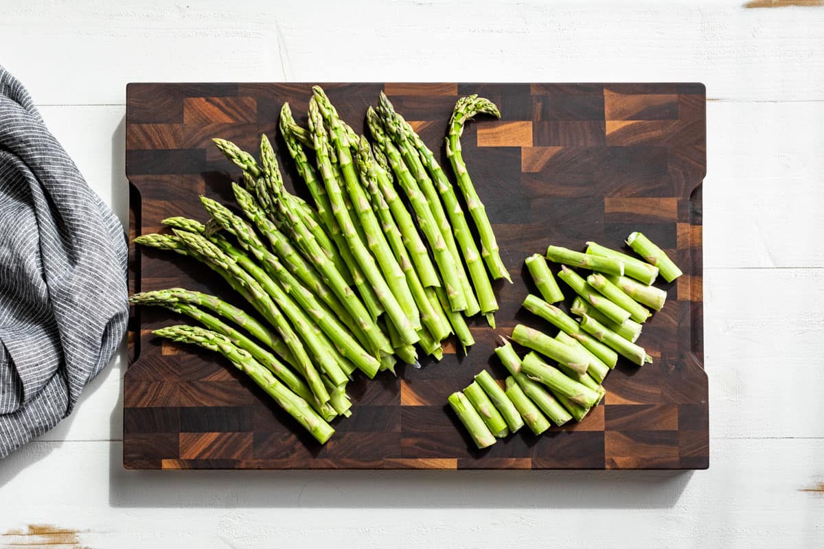 Snapping the ends off the asparagus on a wooden cutting board.