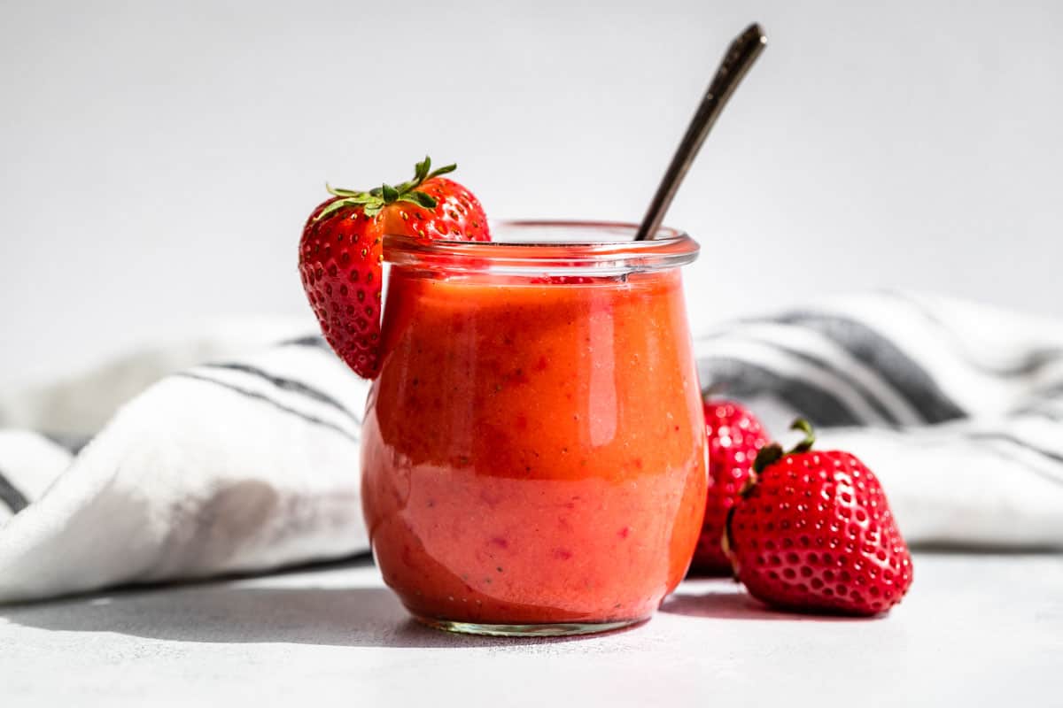 Strawberry Vinaigrette in a clear glass jar with strawberry garnishes.