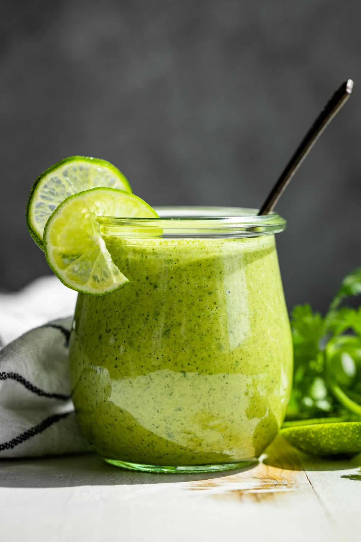 Cilantro Lime Dressing in a glass jar against a grey background.