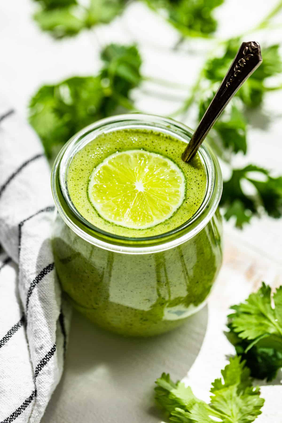 Finished Cilantro Lime Dressing in a glass jar topped with a slice of lime.