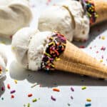 Side view of three chocolate dipped ice cream cones with Coconut Ice Cream and sprinkles.