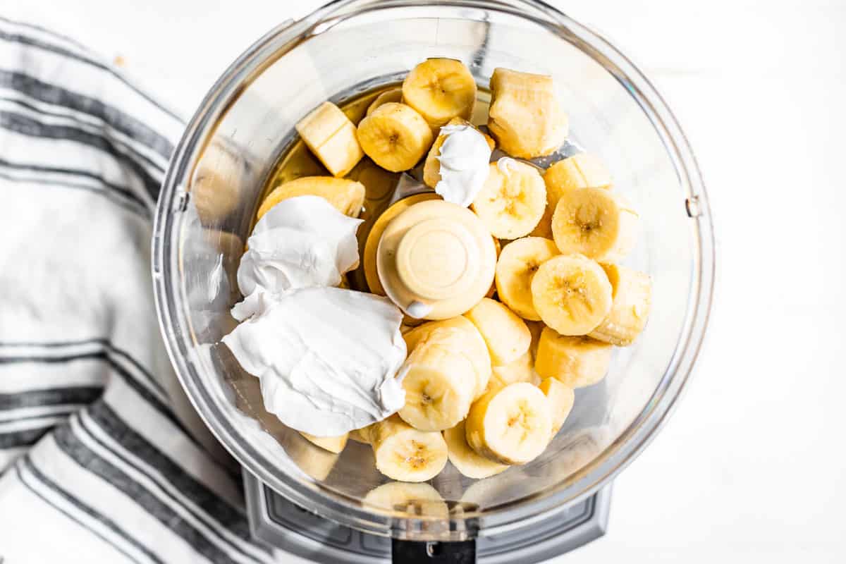 Sliced bananas and coconut cream in a food processor.