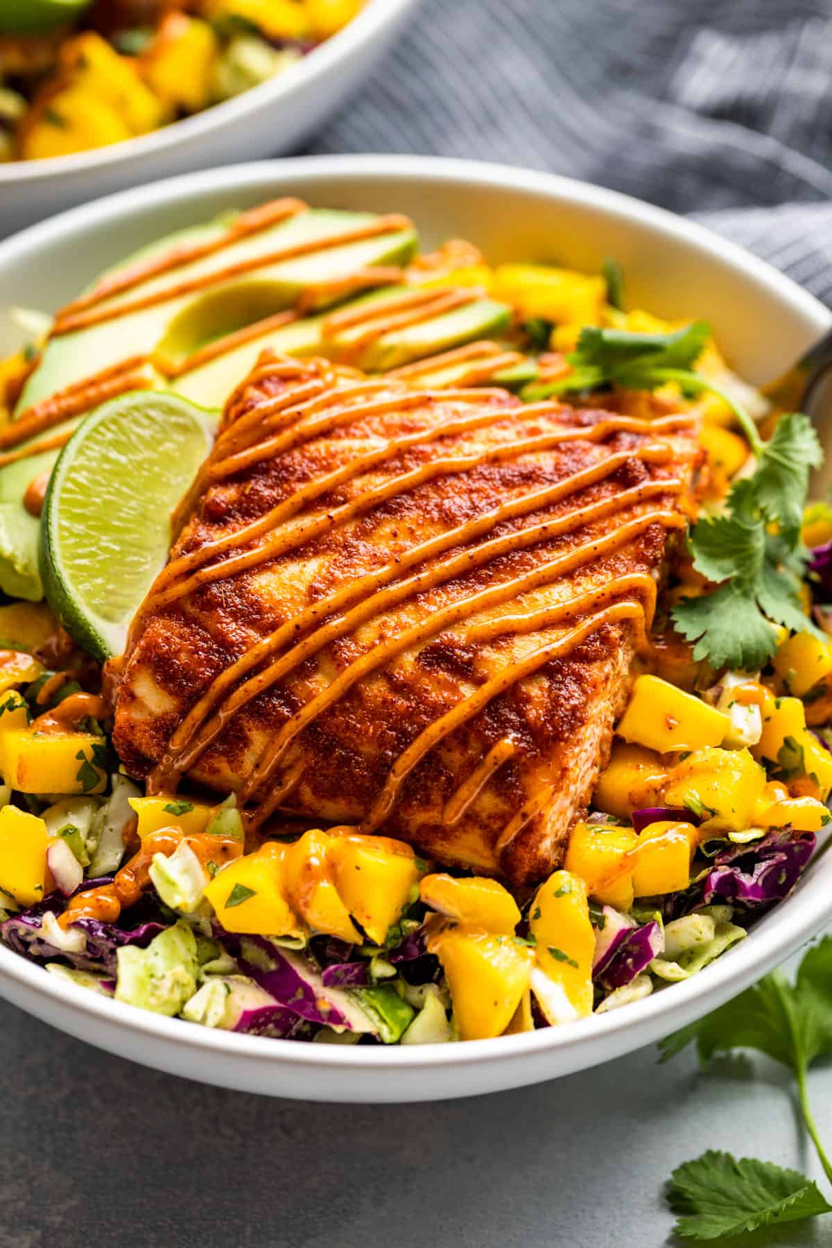 Close macro view of this Fish Taco Bowls topped with Chipotle Aioli and a lime wedge.