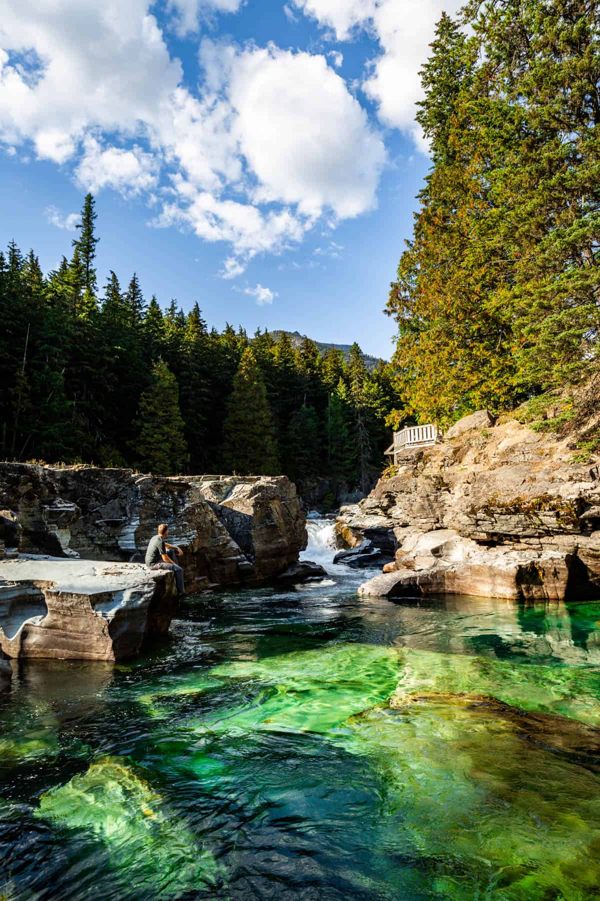 McDonald Creek with a man sitting on the rocks near the water.