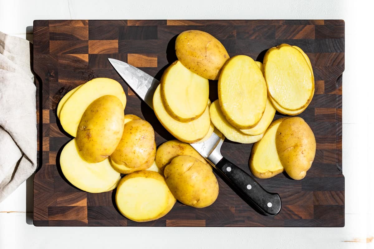 Sliced Yukon gold potatoes on a wood cutting board.