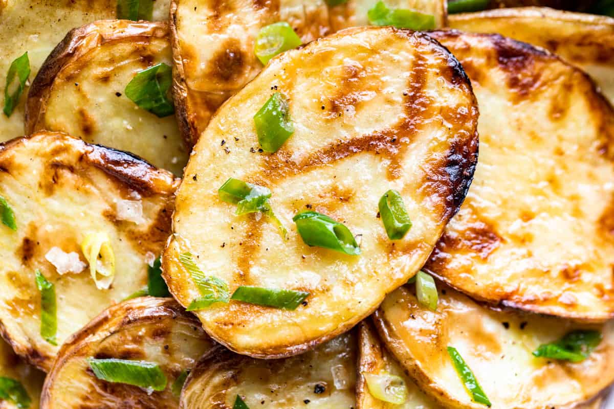 Close macro view of the finished grilled potatoes tossed with the butter and green onions.