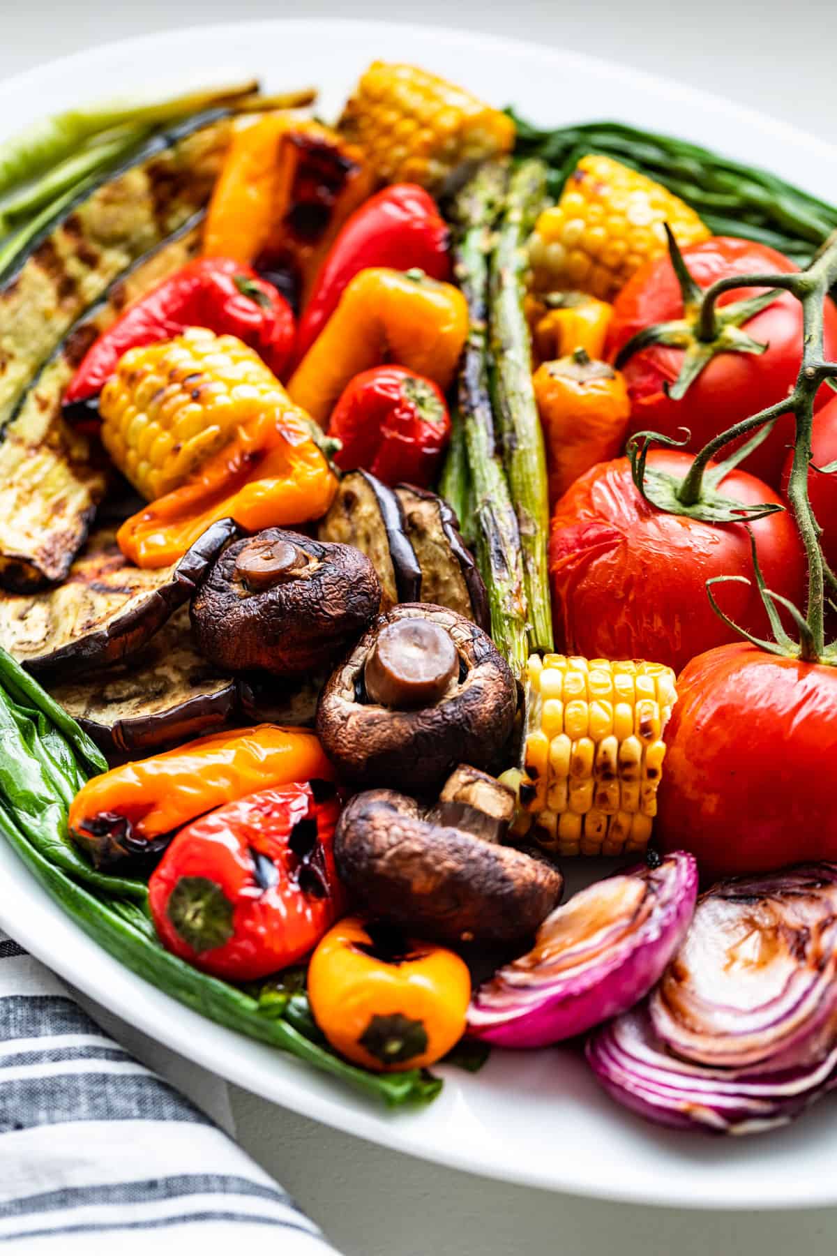 Side view of a large white platter filled with grilled vegetables.