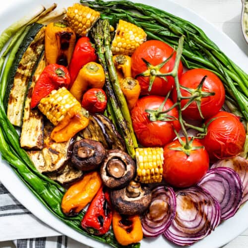 A large white platter filled with the finished grilled veggies and basil aioli on the side.