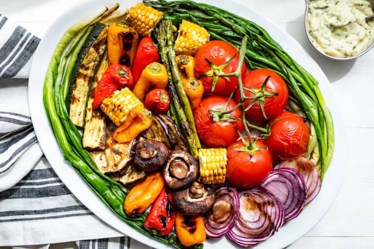 A large white platter filled with the finished grilled veggies and basil aioli on the side.