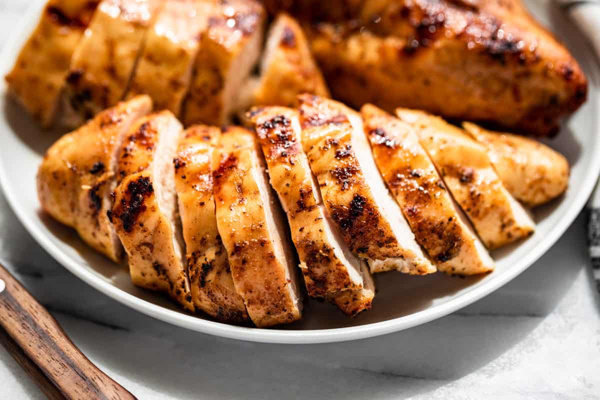 Finished Smoked Chicken Breasts sliced and on a white plate.