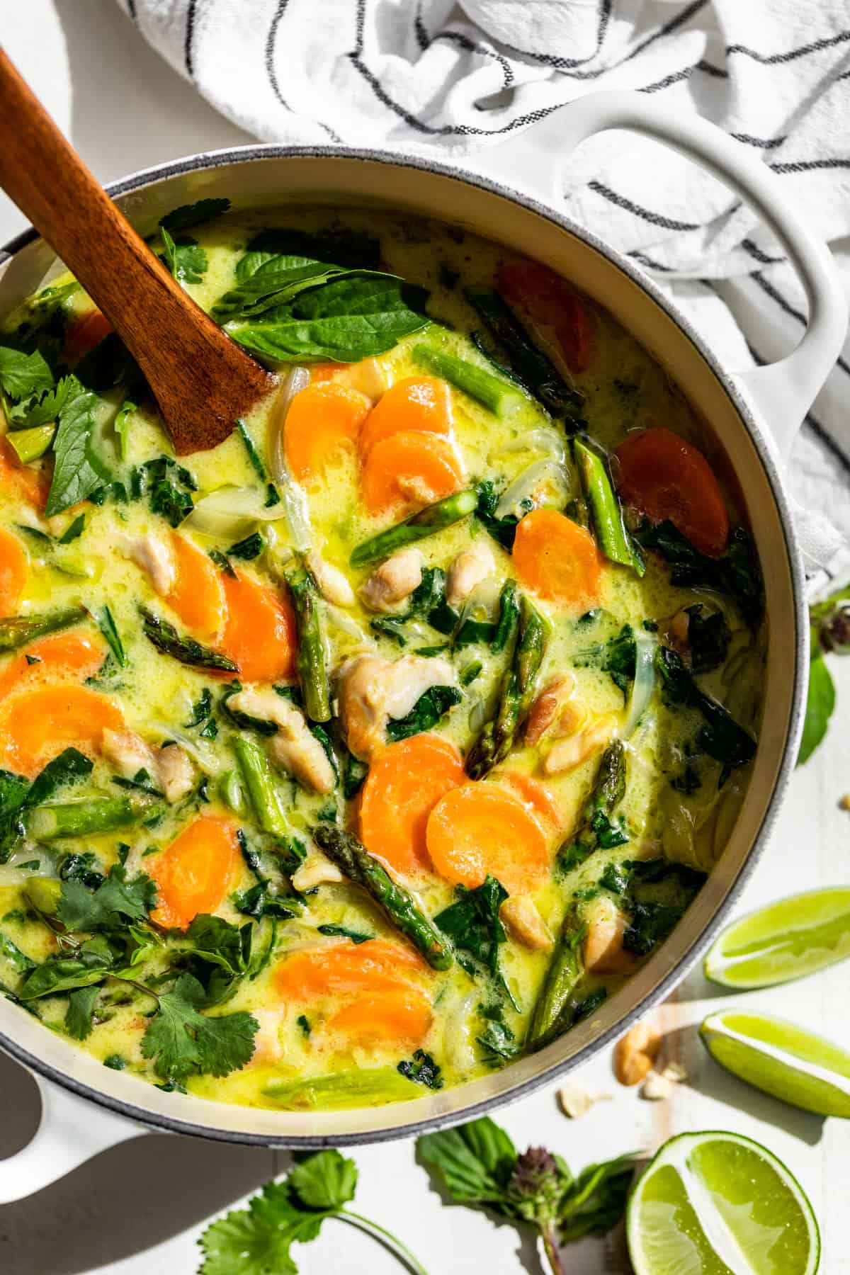 Thai Green Curry in a white pot with a wooden ladle scooping some out.