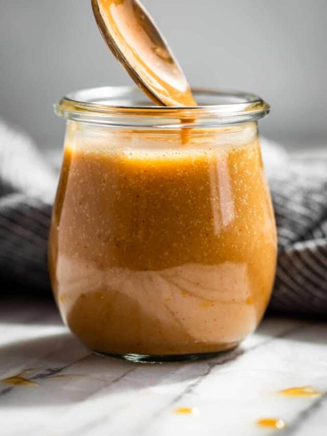 Honey Mustard Sauce in a glass jar with a sliver spoon scooping some out.