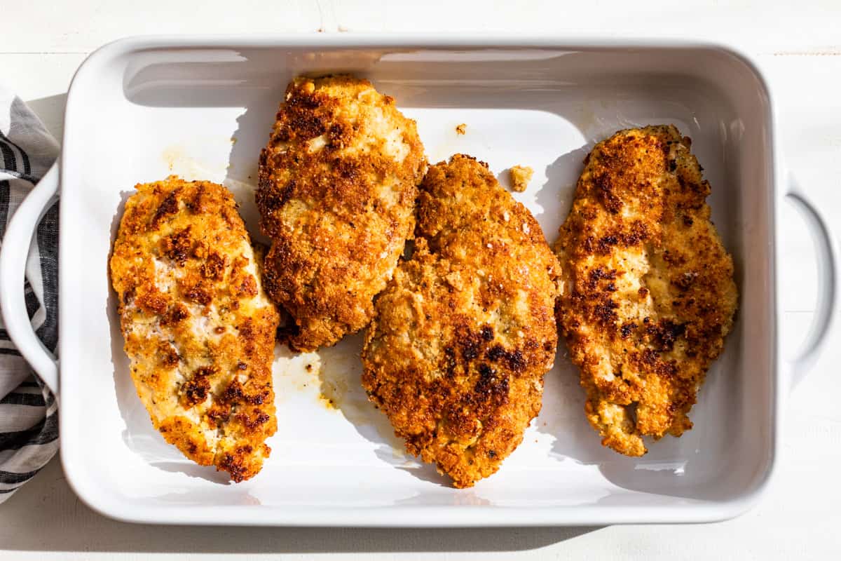 All four breaded chicken cutlets added to the baking dish.