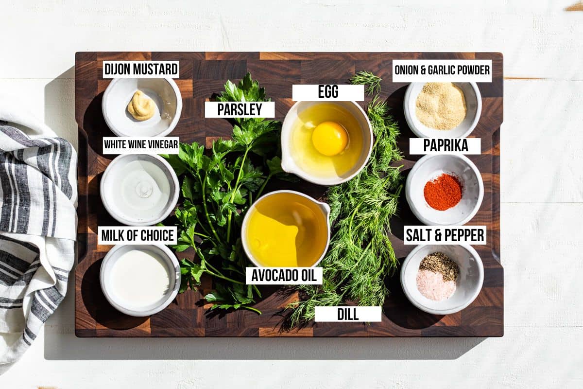 Ingredients for ranch dressing on a wood cutting board, egg, avocado oil, garlic powder, onion powder, paprika, parsley, dill, and Dijon mustard.