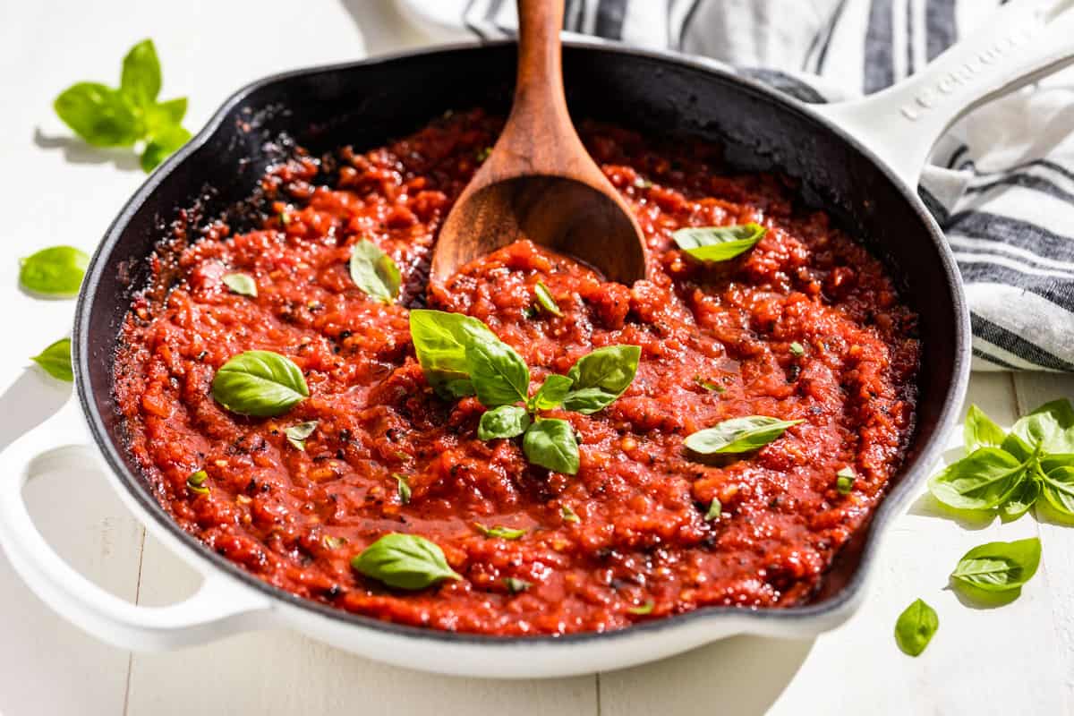 Finished Marinara Sauce in a white skillet topped with sprigs of basil.