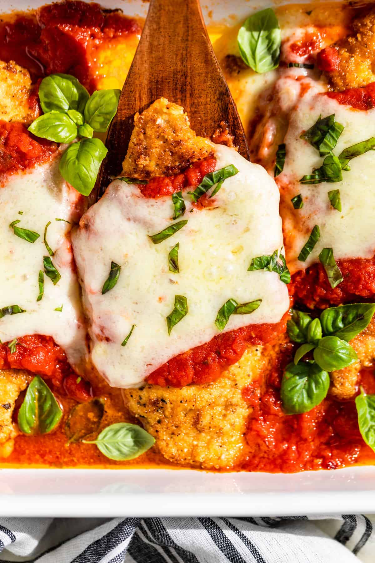 Close up view of a Chicken Parmesan cutlet topped with chopped basil.