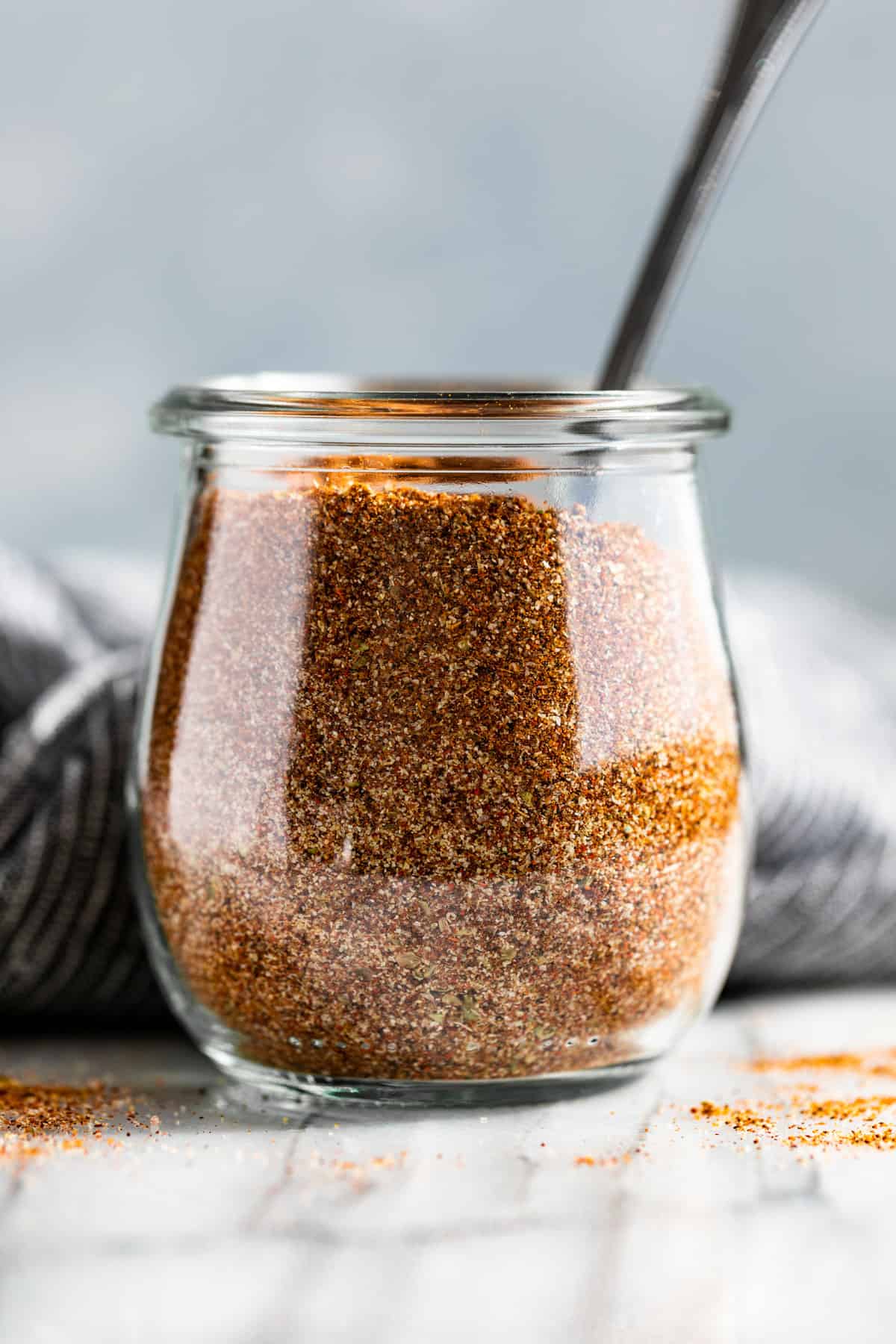 Fajita Seasoning in a glass jar with a sliver spoon in it.