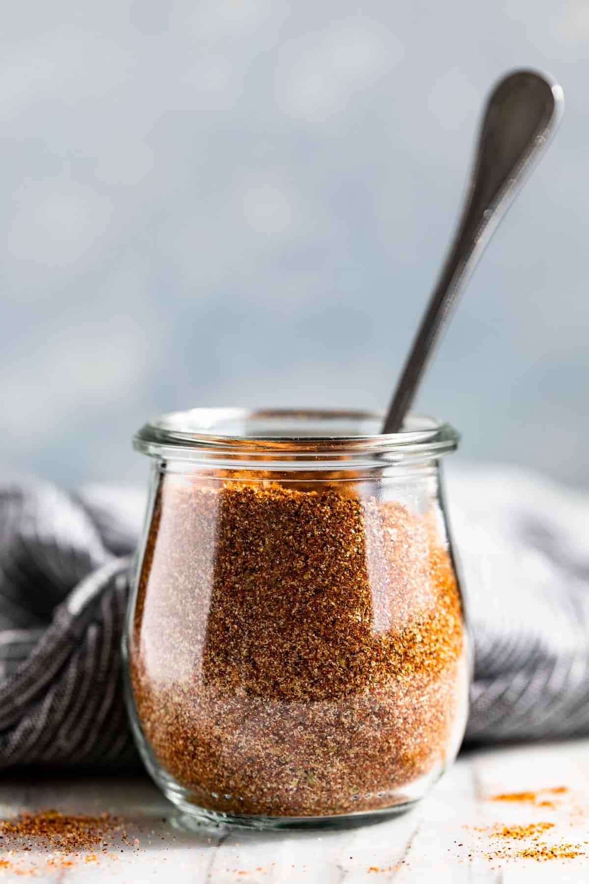 Fajita Seasoning in a glass jar with a blue background.