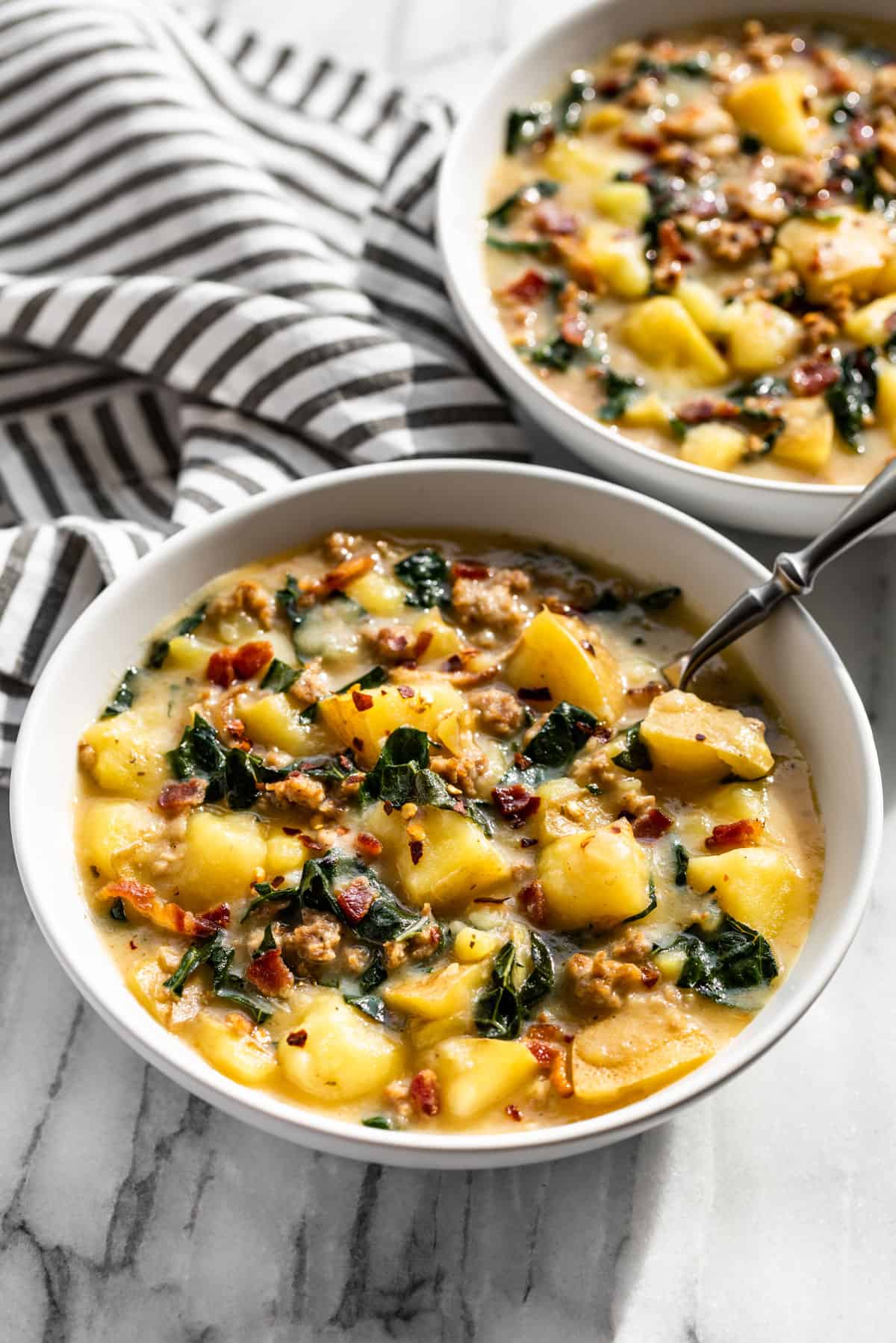 Side view of Zuppa Toscana in two bowls with spoons.