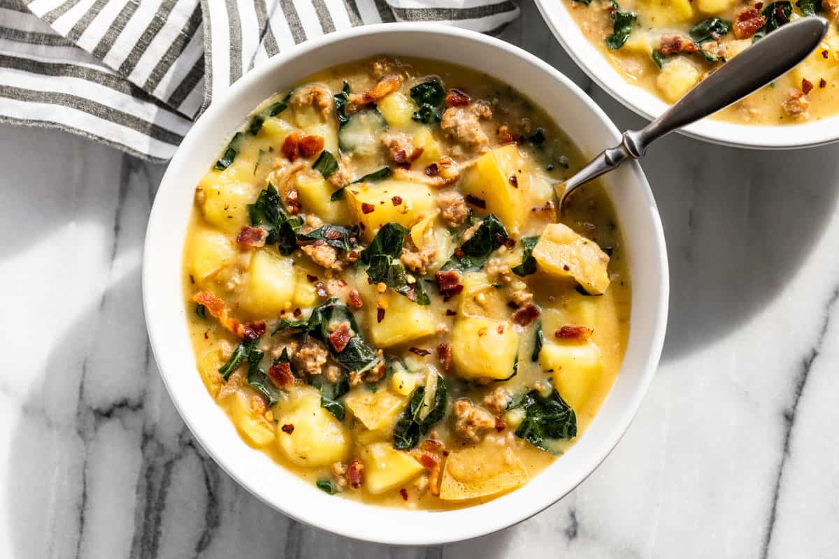 Finished Instant Pot Zuppa Toscana in white serving bowls with a silver spoon in 1 bowl.