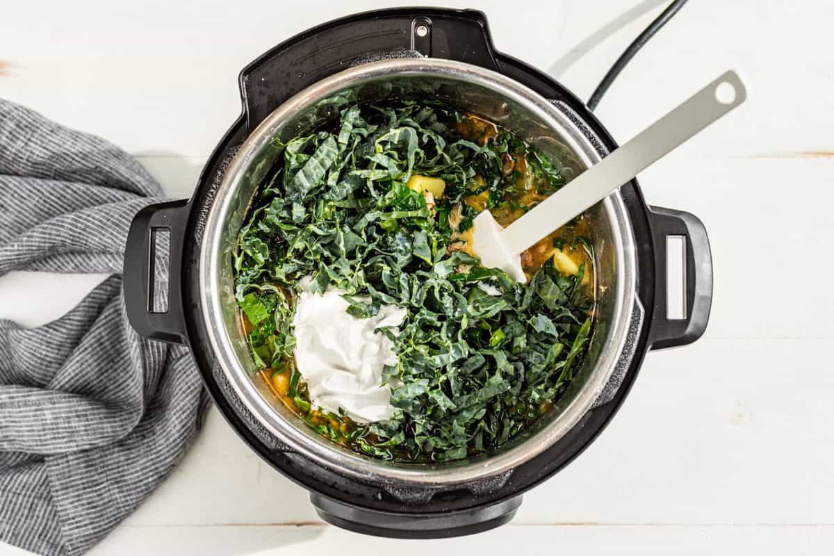 Adding the coconut cream and kale at the end of the cooking time in the Instant Pot.