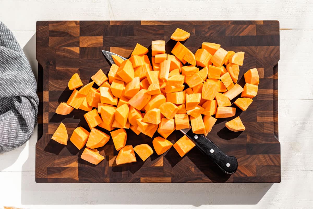 Cubed sweet potatoes on a wood cutting board.