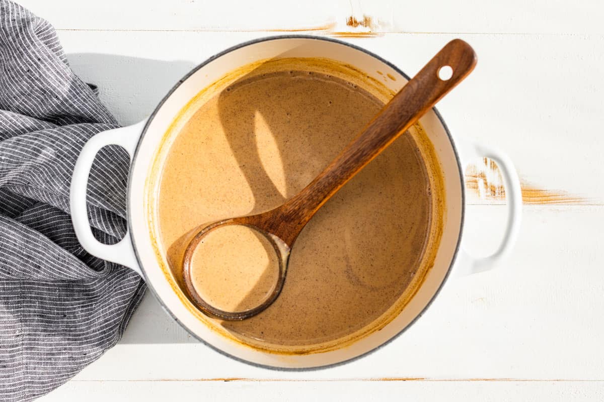 Finished Pumpkin Chai Latte in a white pot with a wood ladle.