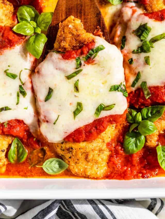 Close up view of a Chicken Parmesan cutlet topped with chopped basil.