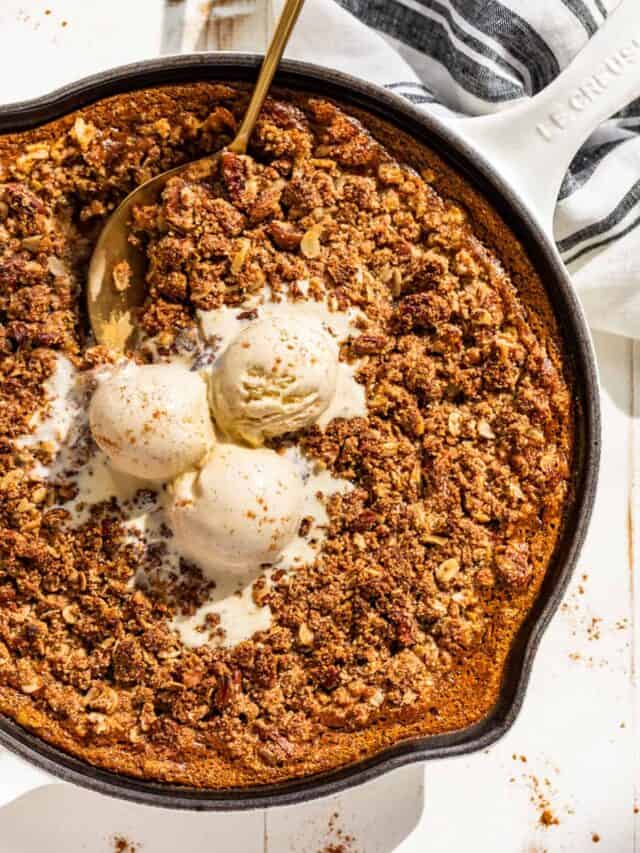 Downwards view of Pumpkin Crisp in a white skillet topped with scoops of ice cream.