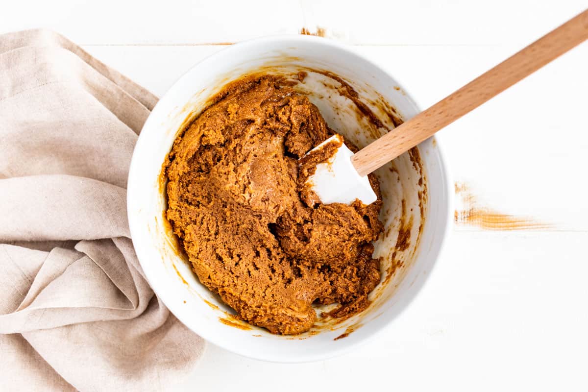 Mixing the peanut butter cookie dough together in a white mixing bowl.