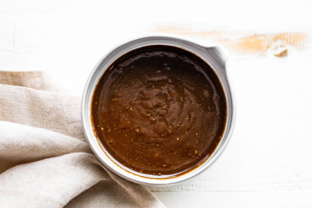 Balsamic vinaigrette in a pottery bowl on a white background.