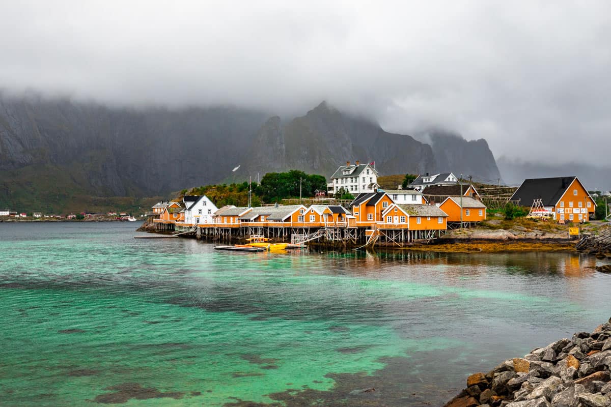 Overcast day with the famous yellow fishing houses on the waterfront in Sakrisoy Norway with turquoise water in the front.