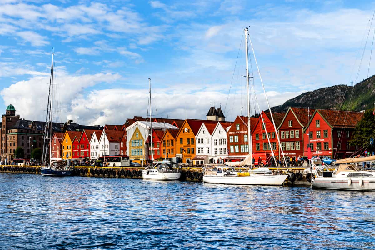 The famous houses by the water called Bryggen in downtown Bergen with sail boats in the front.