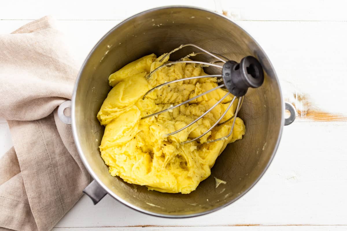 Beating the potatoes together with the butter in a mixing bowl.