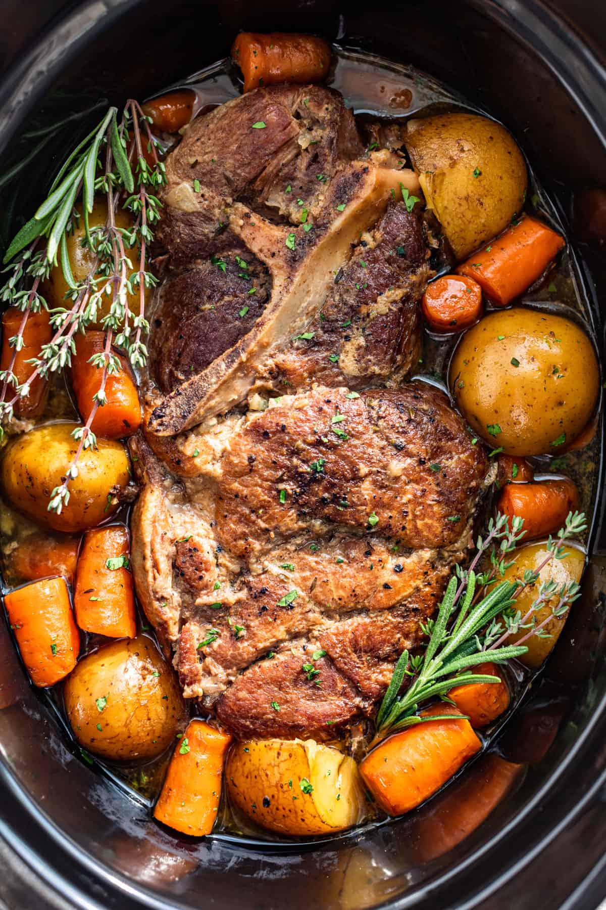 Close up straight down view of Slow Cooker Pork Roast surrounded by carrots and potatoes.