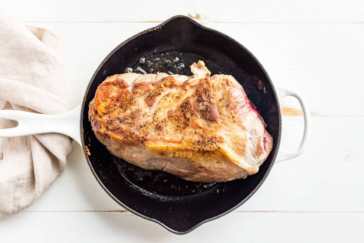 Pan searing the pork roast in a cast iron skillet.