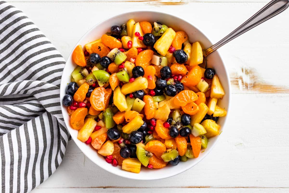 Tossing the fruit salad together with the honey lime dressing.