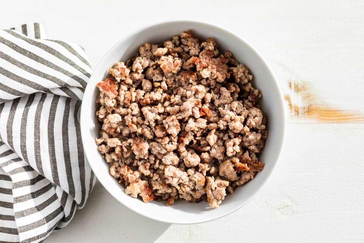 Browned ground pork in a white bowl.